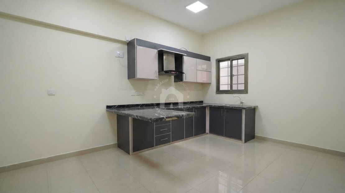 Modern kitchen with dark countertop and cabinets in PECHS Block 2 furnished apartment, Karachi Residencies